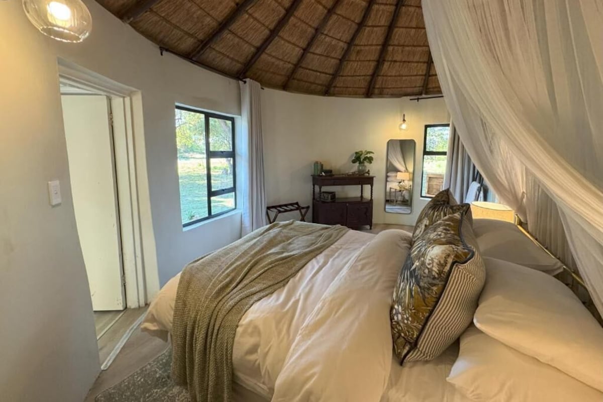 Un dormitorio con cama, espejo, mesita de noche y ventana.