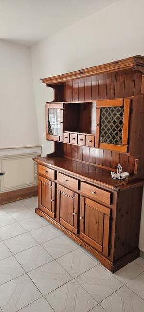 A wooden cabinet with multiple drawers and a glass door with a lattice pattern.