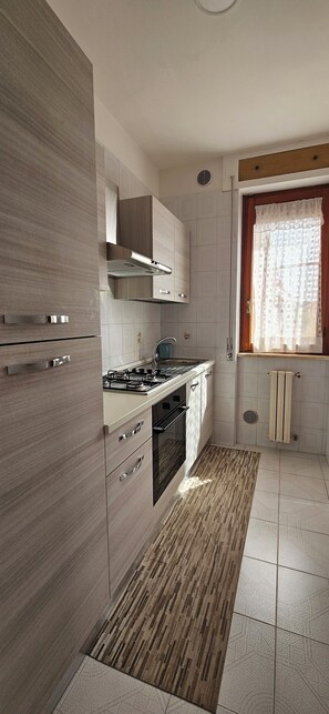 Een moderne keuken met een ingebouwde oven, een gasfornuis en een afzuigkap.