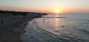 A beach with people, tents, and a sunset.