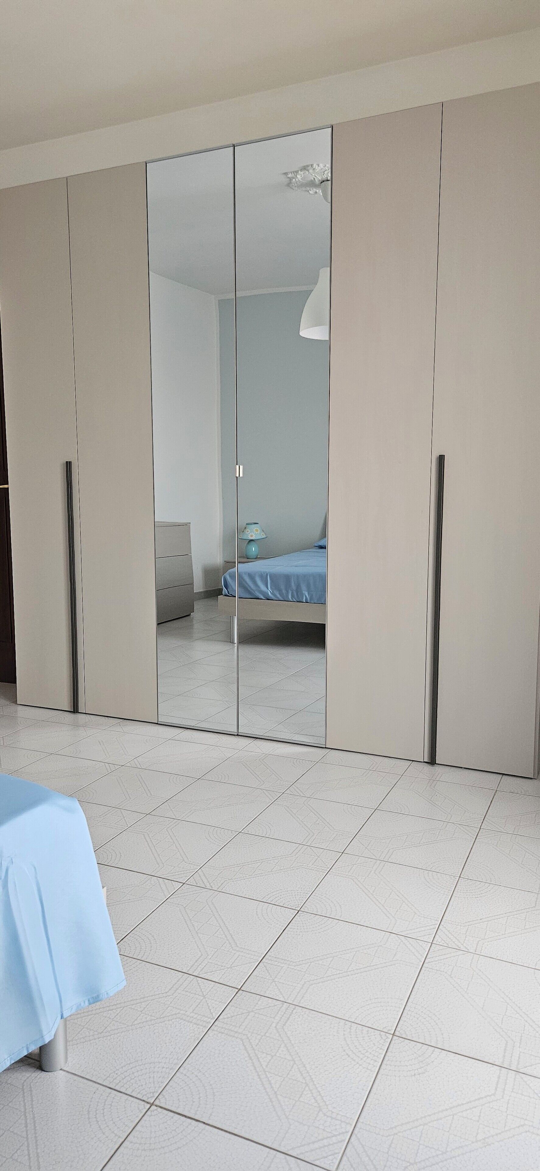 Ein Schlafzimmer mit einem Bett, einem Kleiderschrank und einem Spiegel.
