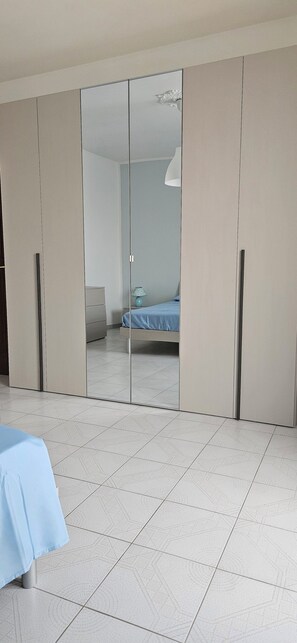 Een slaapkamer met een bed, een kledingkast en een spiegel.