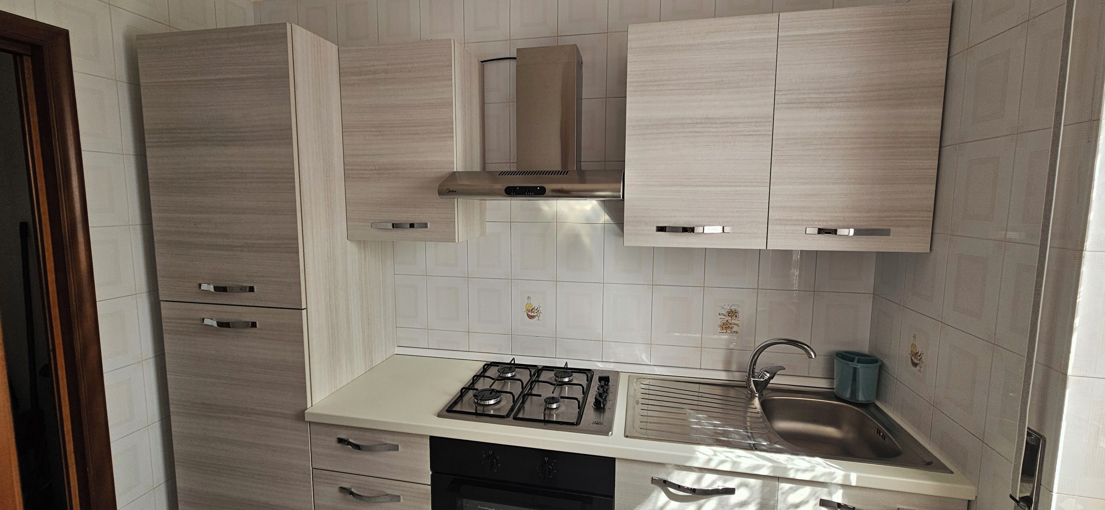 A compact kitchen with a gas stove, a sink, and cabinets.