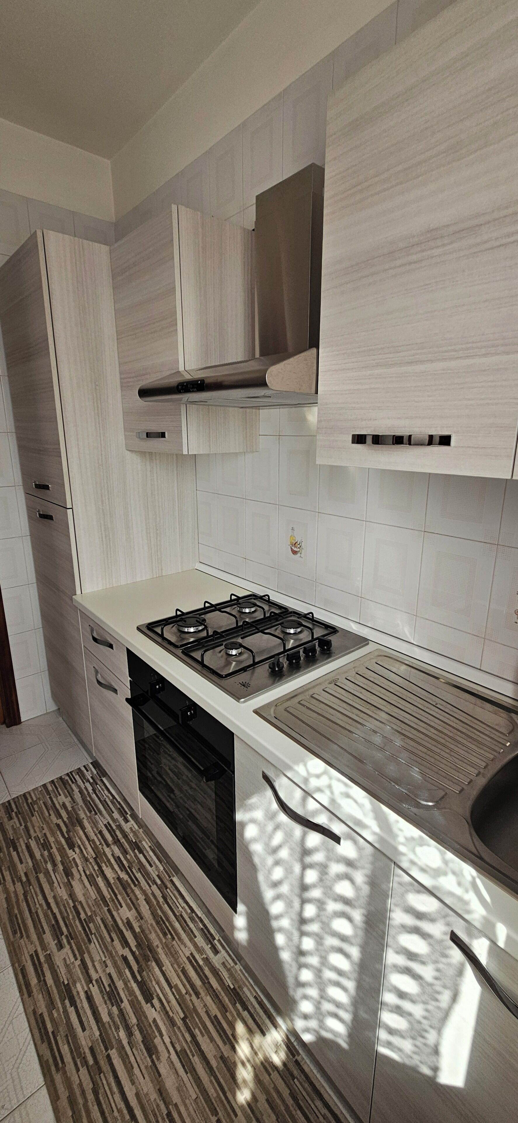 Une cuisine moderne équipée d’une cuisinière à gaz, d’un four et de meubles de rangement blancs.