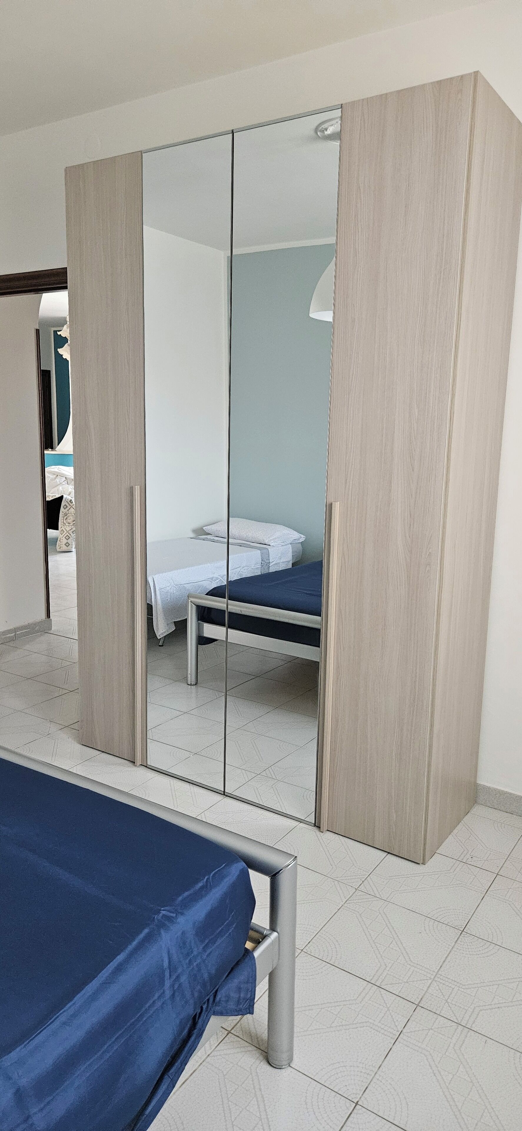 Un dormitorio con cama, armario y espejo.