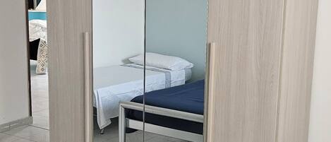 Un dormitorio con cama, armario y espejo.