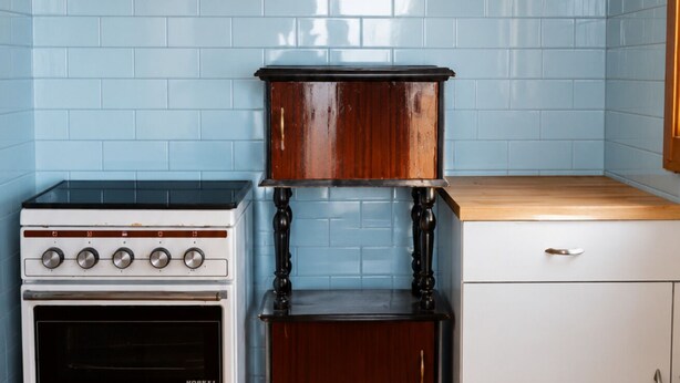 A kitchen with a white stove, a wooden cabinet, and a white countertop.