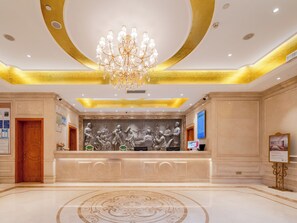 A lobby with a grand chandelier, a reception desk with a relief sculpture, and a marble floor. - Vienna Hotel (Shenzhen)