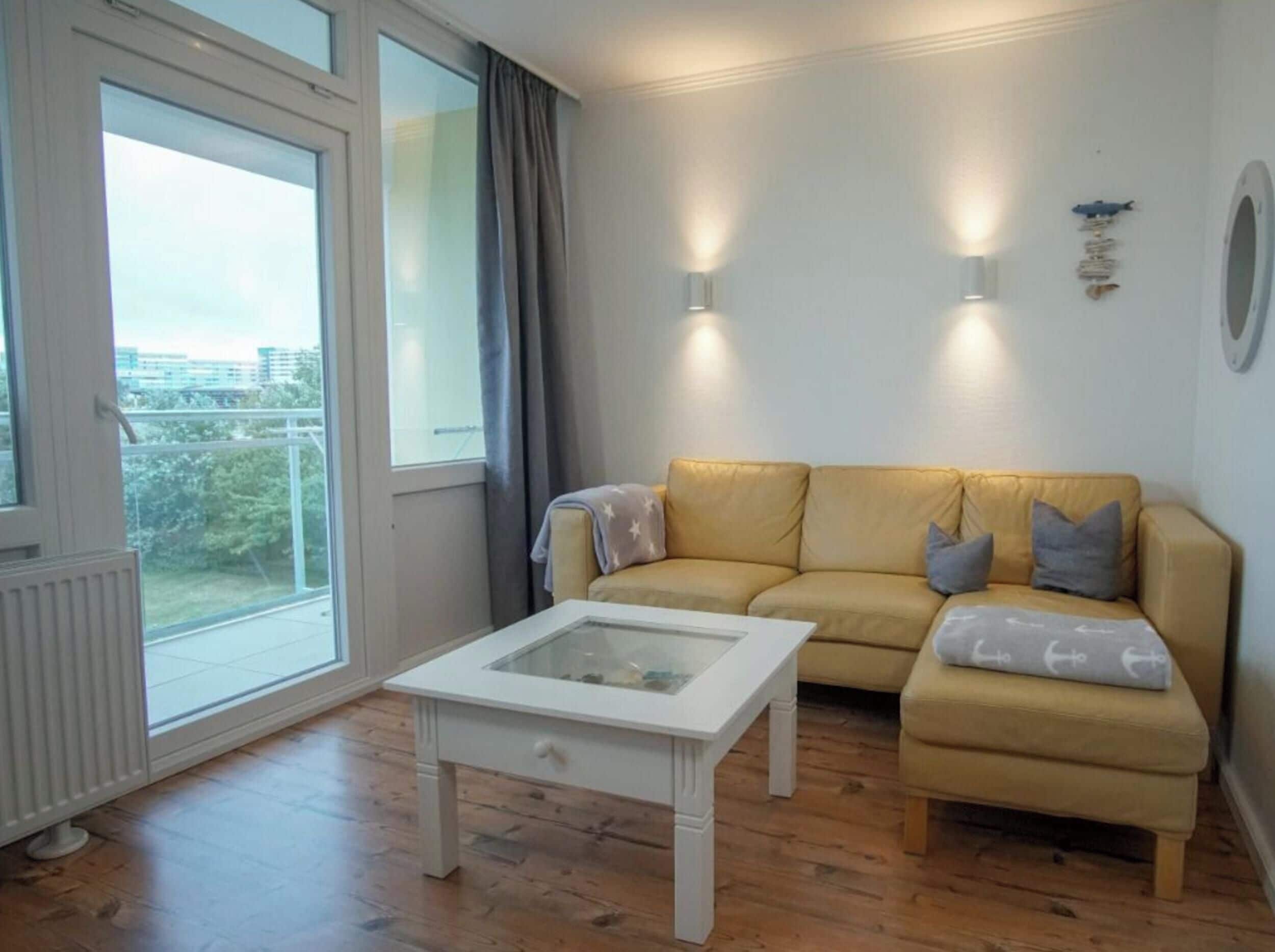 A living room with a sofa, a coffee table, and a view through a large window.