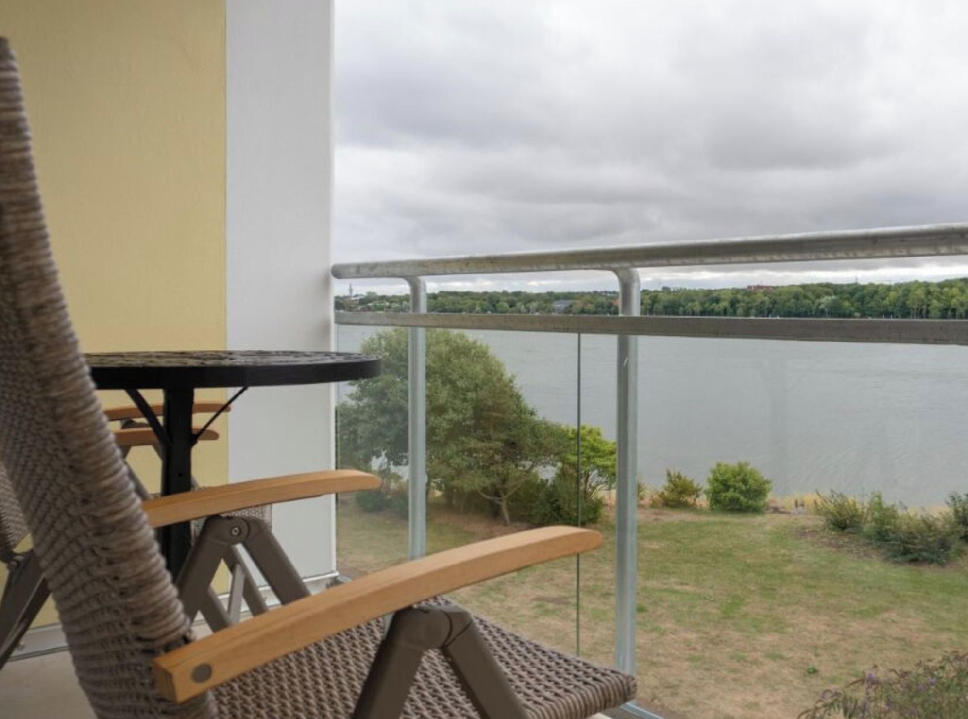 Un balcon donnant sur un lac, avec une chaise et une table.