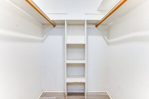 A narrow, white-walled closet with a wooden ladder and shelves.