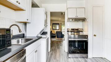 A modern kitchen with white cabinetry, a built-in oven, and a stainless steel range hood.