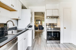 A modern kitchen with white cabinetry, a built-in oven, and a stainless steel range hood.