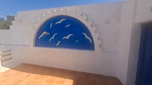 Un mur blanc sur lequel est peint un ciel bleu et des oiseaux blancs.
