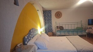 A bedroom with a bed, a small table, a television, and a wall-mounted circular decoration.