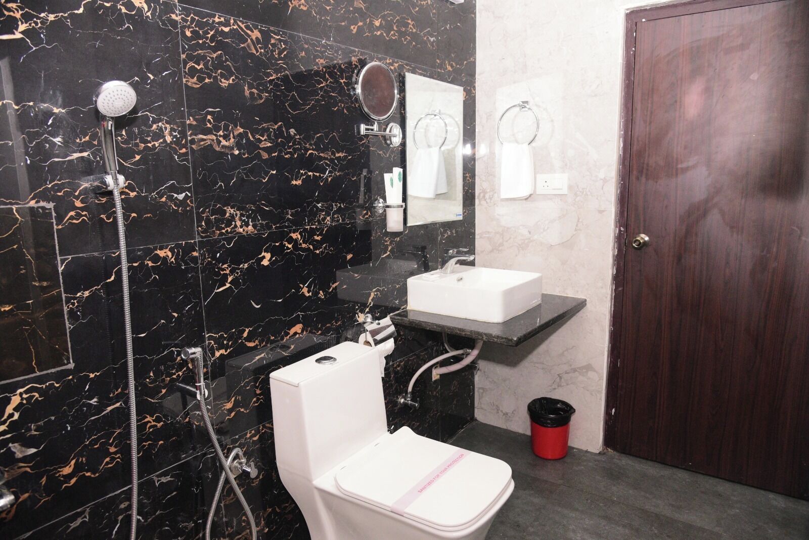 A bathroom with a white toilet, a sink, a shower, and a mirror.