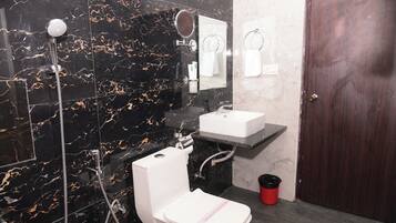 A bathroom with a white toilet, a sink, a shower, and a mirror.