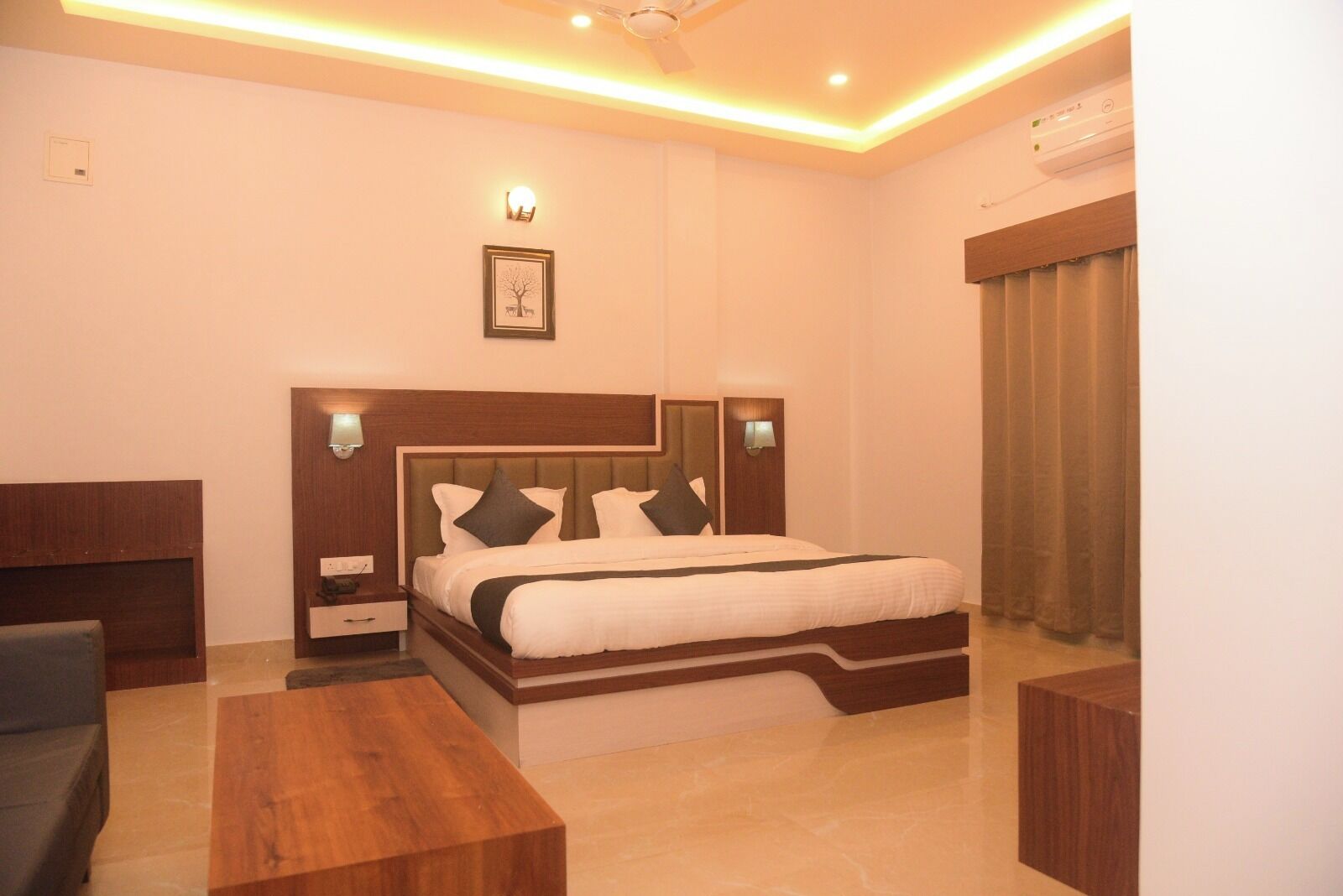 A hotel room with a bed, bedside tables, a desk, and a ceiling fan.