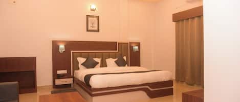A hotel room with a bed, bedside tables, a desk, and a ceiling fan.