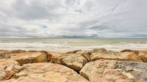 Ein felsiger Strand mit Wellen und bewölktem Himmel.