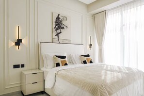 Una habitación de hotel con una cama grande, mesitas de noche, una obra de arte en la pared y una ventana con cortinas.