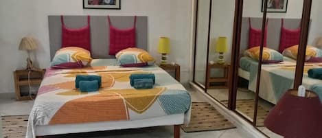 A bedroom with a bed, bedside tables, a mirror, and a window.