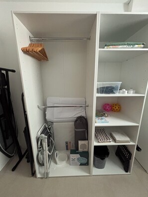 A white closet with shelves, a hanging rack, and a baby changing station. - Charming vacation rental (Cublac)