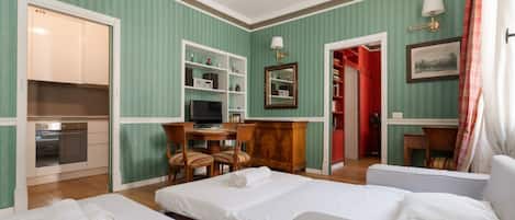 A hotel room with two beds, a desk with a computer, a TV, a mirror, and a wardrobe.