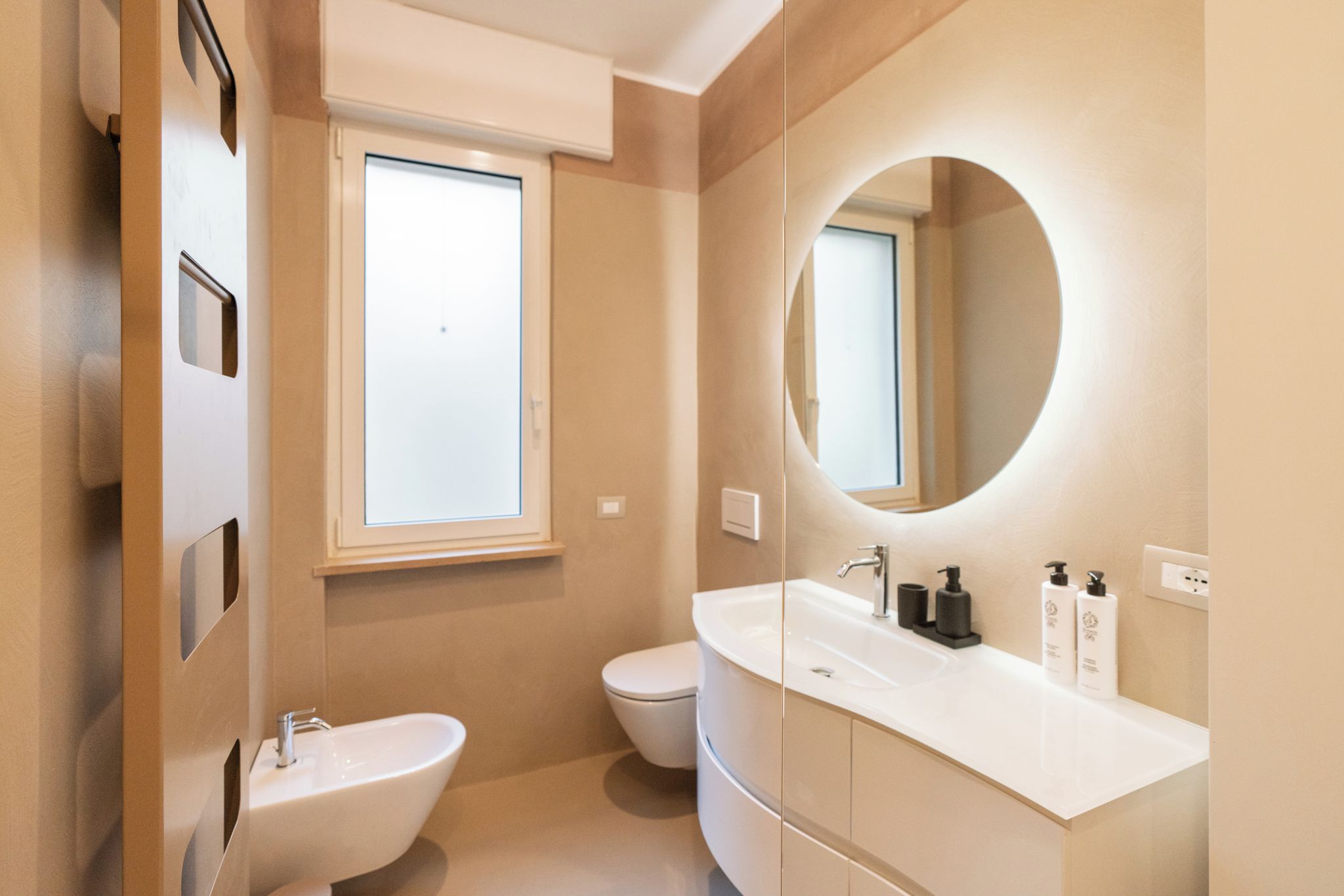 Un baño moderno con bidé, inodoro y un espejo grande.