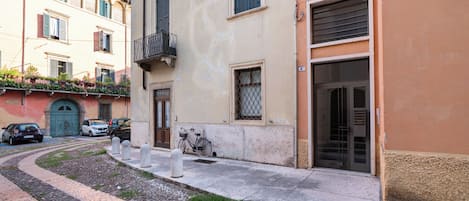A narrow street with buildings, a bicycle, and parked cars.