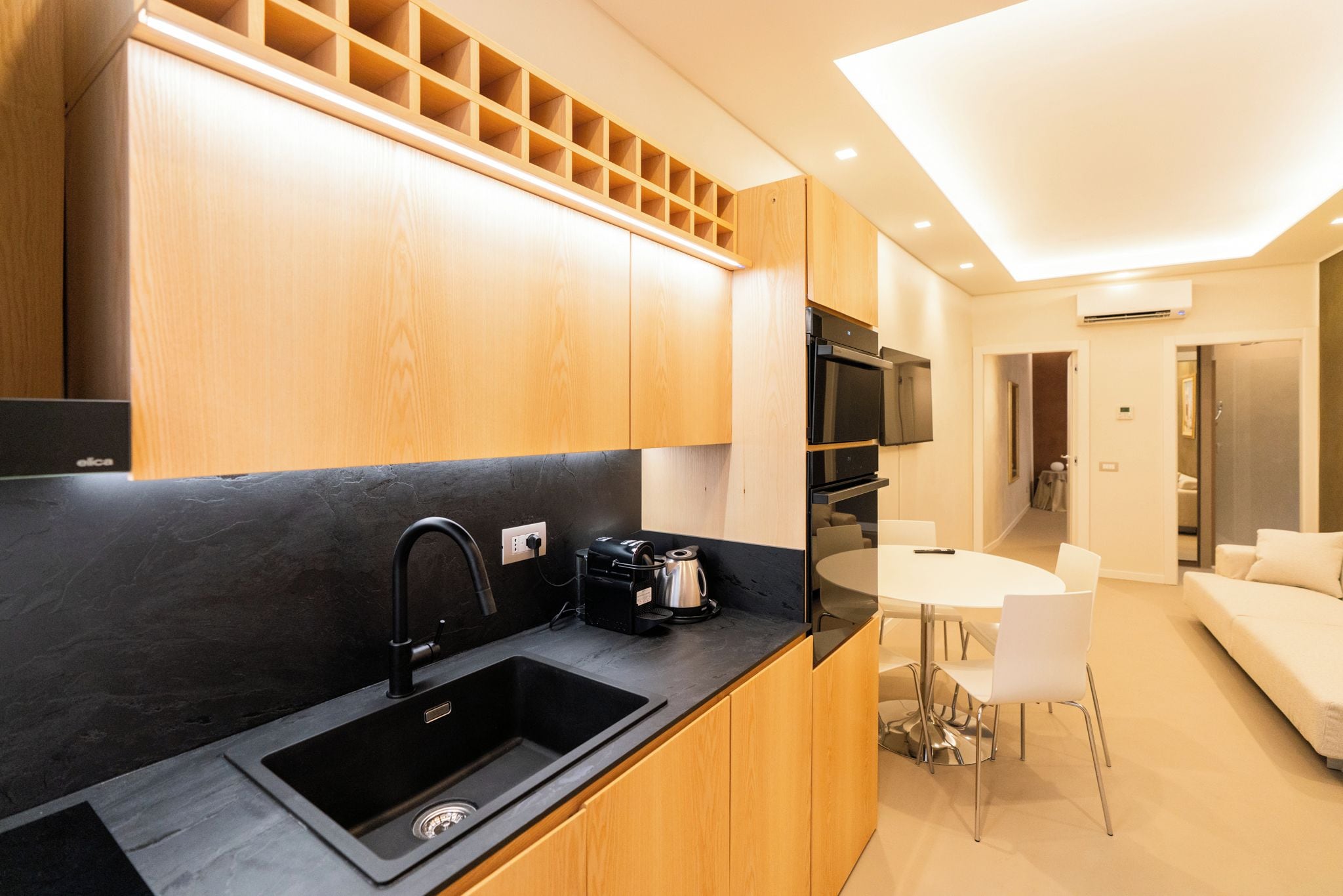 A modern kitchen with a black sink, wooden cabinets, and a built-in microwave.