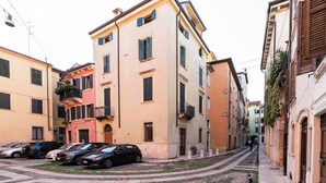 A narrow street with parked cars and buildings with balconies. - Residenza De Nicolis - 50mt Piazza Erbe (Verona)
