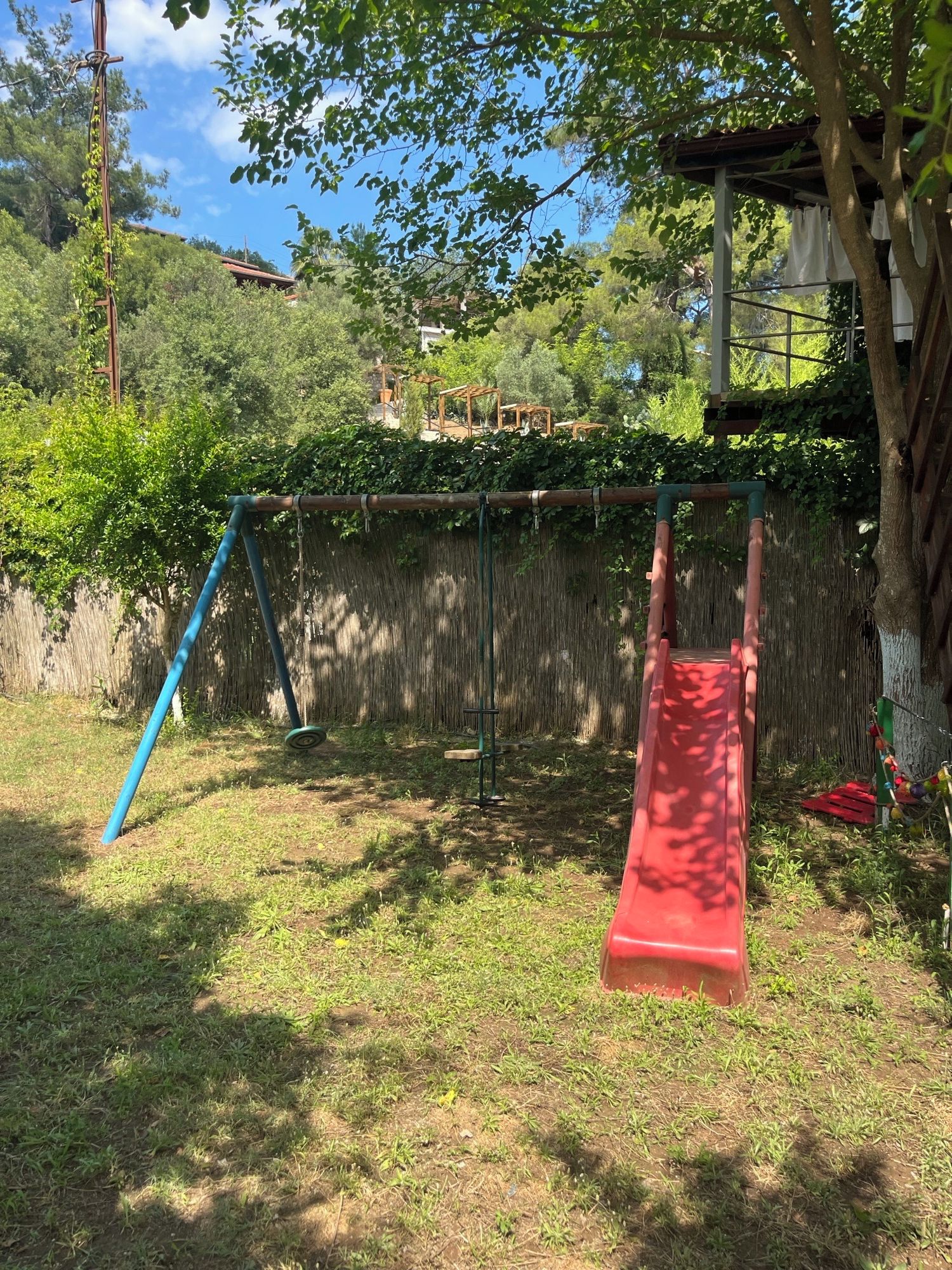 Un parque infantil con tobogán y columpios en un área verde.