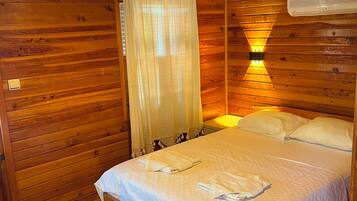 Ein Schlafzimmer einer Holzhütte mit einem Bett, einer Hängeleuchte und einem Fenster mit Blick.