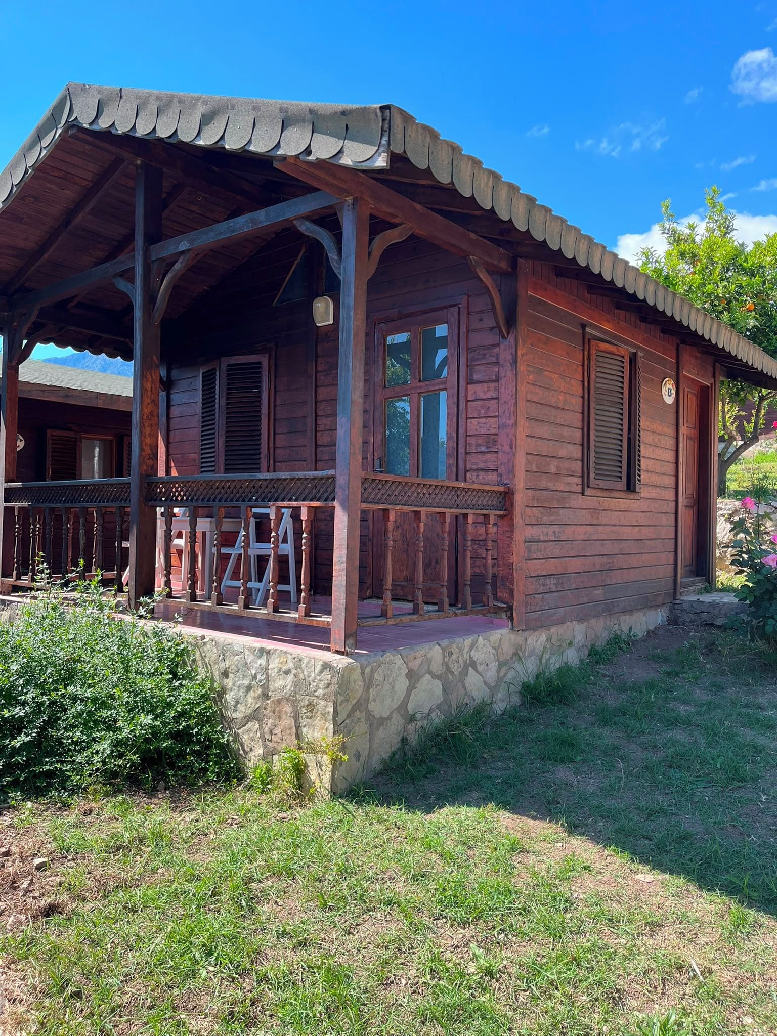 Eine Holzhütte mit Veranda, Stein Fundament und blauem Himmel.