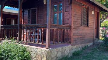 A wooden cabin with a porch, stone foundation, and a clear sky.