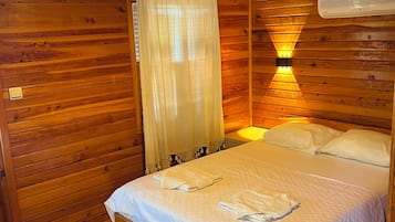 Un dormitorio de cabaña de madera con una cama, una lámpara colgante y una ventana con vistas.