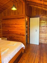 Una habitación de madera con una cama, un armario y una lámpara colgante.