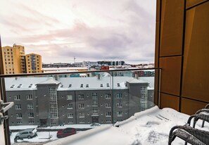 A snowy balcony with a view of a cityscape, including multi-story buildings and parked cars. - SIF Apartments Reykjavik - Two Floors 1 Bedroom (Reykjavík)