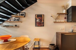 A modern kitchen with wooden shelves, a dining table, and a staircase. - SIF Apartments Reykjavik - Two Floors 1 Bedroom (Reykjavík)