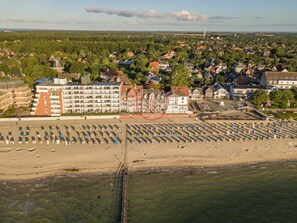 A coastal town with a prominent hotel featuring multiple floors and a beach area with umbrellas. - Holiday Apartment With 1 Bedroom (Wyk auf Foehr)
