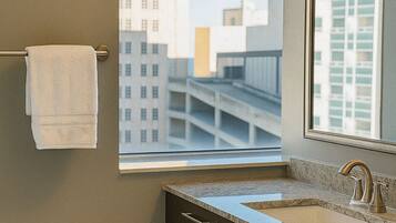 A bathroom with a window, a towel rack, a sink, and a mirror.