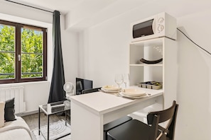 Habitación compacta con una mesa de comedor, sillas, microondas y ventana con vistas a zonas verdes.