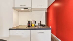 A kitchenette with a coffee maker, kettle, and a bottle on the counter. - L'érable - Charming Studio Near Île Barbe (Lyon)