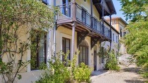A two-story building with a balcony, windows, and a gravel pathway. - L'érable - Charming Studio Near Île Barbe (Lyon)