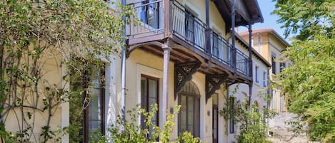 A two-story building with a balcony, windows, and a gravel pathway.