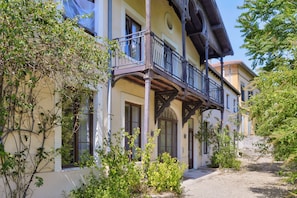 Ein zweigeschossiges Gebäude mit einem Balkon, Fenstern und einem Kiesweg.