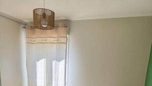 A bedroom with a bed, a radiator, a window with curtains, and a potted plant. - Le Chêne - Charming Apartment with a Garden (Lyon)