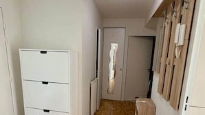 A hallway with a white cabinet, a bench, and a wooden floor. - Le Chêne - Charming Apartment with a Garden (Lyon)