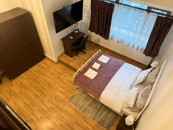 Une chambre à coucher comprenant un lit, un bureau, une télévision et une armoire.